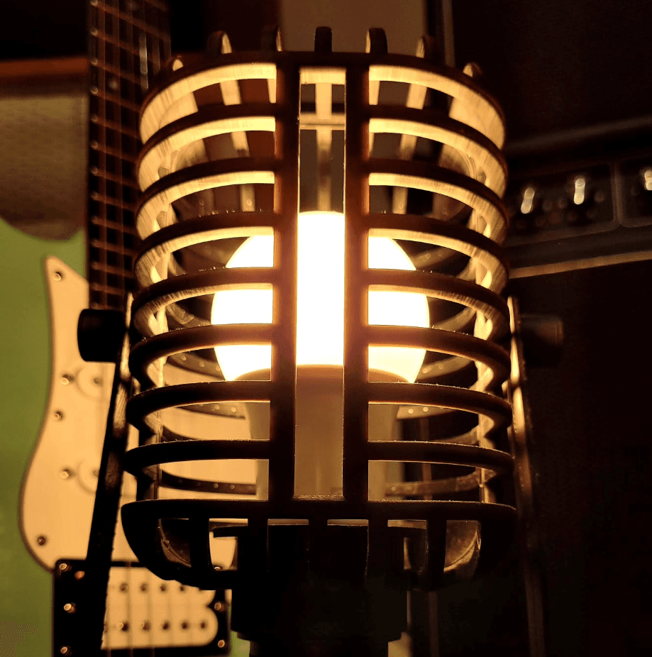 Pantalla de lámpara de listones impresa en 3D, encendida, con una guitarra al fondo