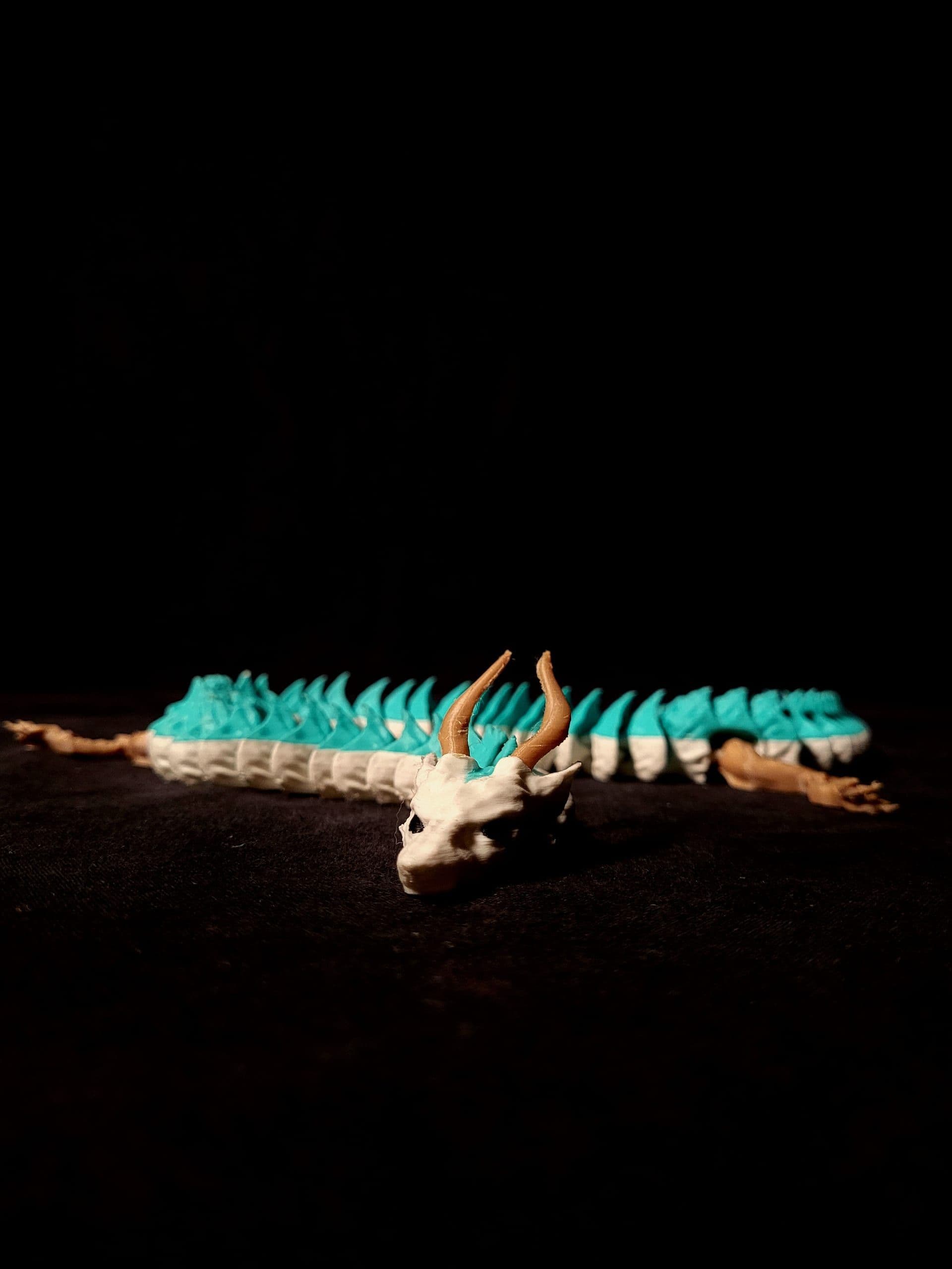 Dragón articulado turquesa y blanco con cuernos cobrizos